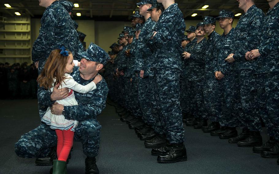 Machinist's Mate 1st Class John Rasmussen, from Sacramento, Calif., hugs his daughter Lillian during a frocking ceremony in USS John C. Stennis' hangar bay Dec. 9, 2015.