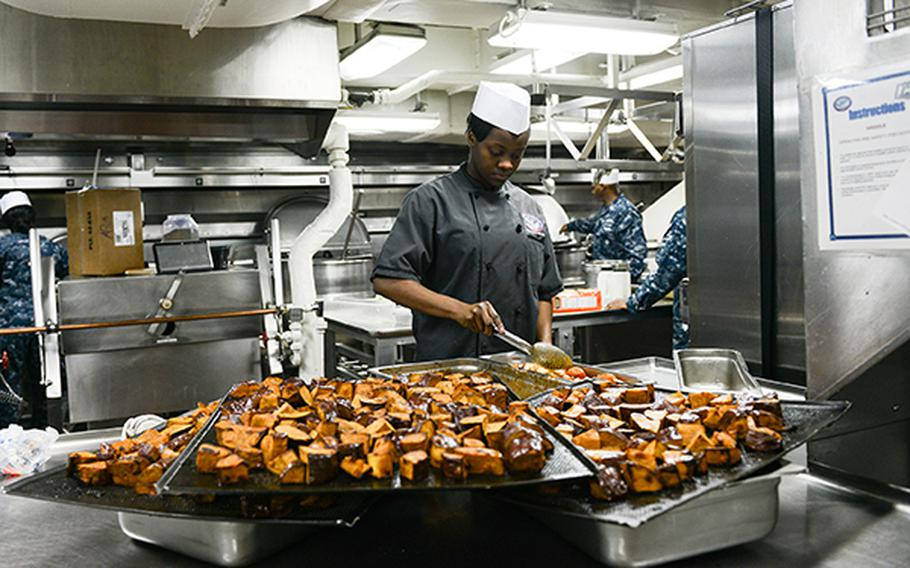 Culinary Specialist Seaman Shanit Cooper, from Florence, S.C., prepares candied yams for a Christmas meal in the aft galley of the U.S. Navy's only forward-deployed aircraft carrier USS Ronald Reagan Dec. 25, 2015.