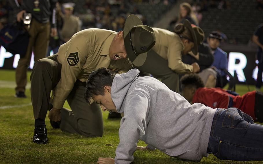 Staff Sgt. Hugo Ramirez, a U.S. Marine drill instructor from Marine Corps Recruit Depot San Diego, motivates a game attendee after the 1st quarter in a push-up challenge at the Semper Fidelis All-American Bowl at the Stubhub Center, Carson, Calif., Jan. 3, 2016.