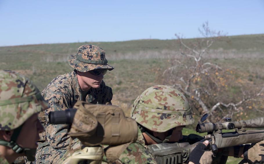 U.S. Marine Sgt. Mason Wilhelmy, primary marksmanship instructor with the Pre-Scout Sniper Course, 1st Marine Division Schools, observes the shooting form of a Japan Self-Defense Force soldier, during an unknown distance course of fire, at Marine Corps Base Camp Pendleton, Calif., Jan. 28, 2016.