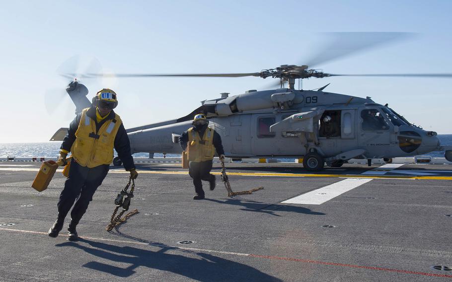 Sailors recover chocks from a MH-60S Sea Hawk helicopter attached to Helicopter Sea Combat Squadron 25 on the flight deck of the amphibious assault ship USS Bonhomme Richard during flight operations Jan. 22, 2016.