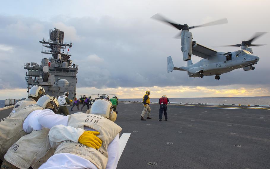 Marines assigned to combat cargo aboard the amphibious assault ship USS Bonhomme Richard brace for the wind as an MV-22 Osprey attached to Marine Medium Tiltrotor Squadron 265 lands on the flight deck Jan. 25, 2016.
