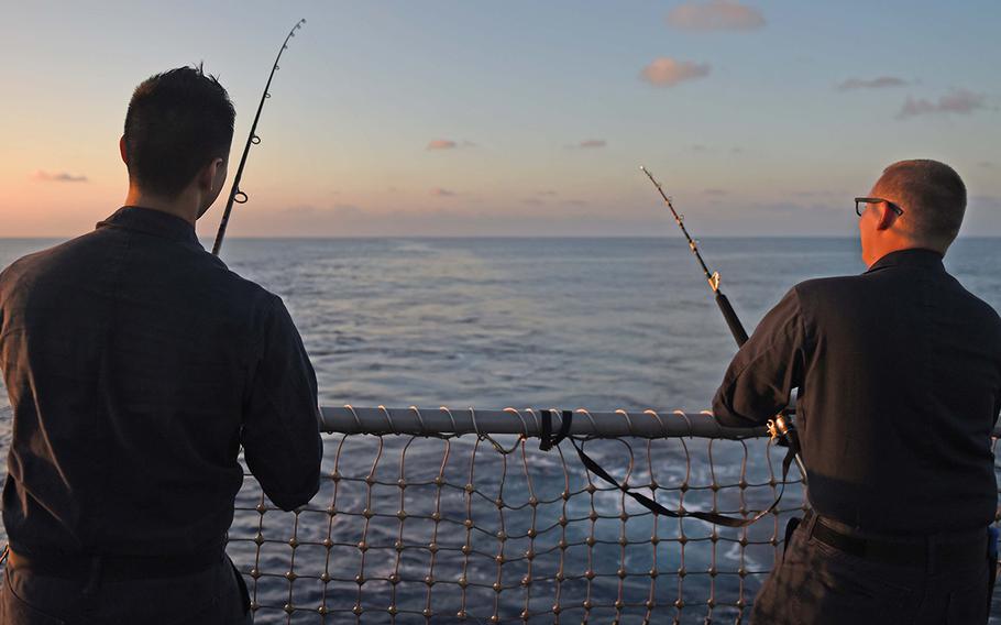 Seaman Dennis Tran, from Riverside, Calif., and Petty Officer 2nd Class Darryl Roberson, from Joliet, Ill., fish off the stern of the guided-missile destroyer USS Stockdale during a fish call Jan. 26, 2016.