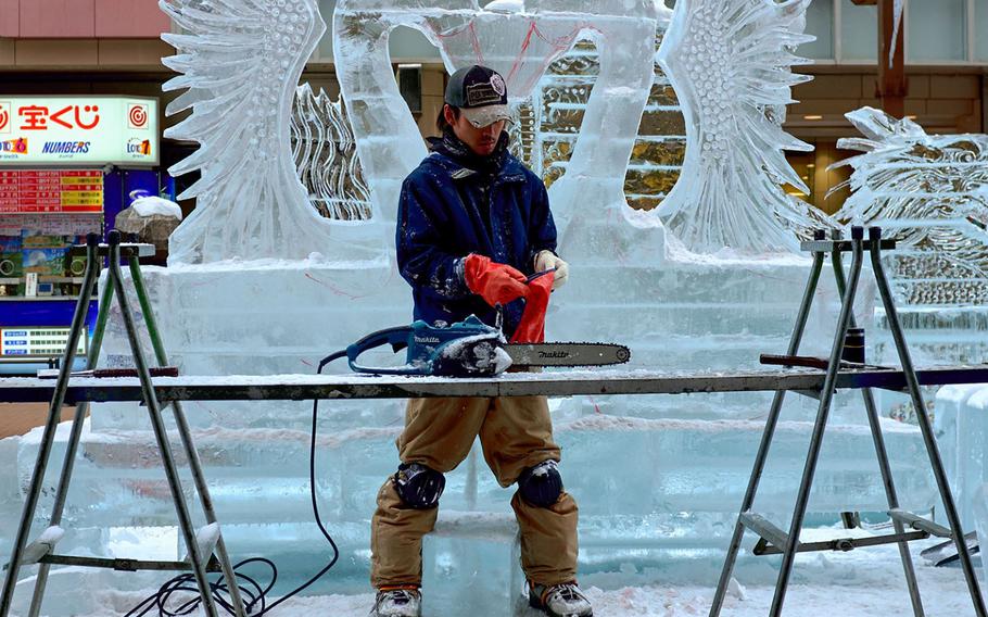 An ice sculptor puts on safety gloves before cutting ice off of his sculpture in Sapporo, Japan's Susukino District Feb. 3, 2016. The Sapporo Snow Festival is scheduled to start Friday, Feb. 5 with the final displays being taken down by February 18.