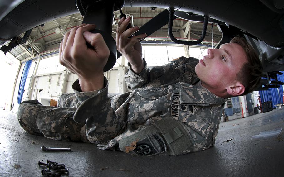 Pfc. Tristan Lehman, AH-64 Apache helicopter repairer with 122nd Aviation Support Battalion, 82nd Combat Aviation Brigade, works to remove the radar altimeter to prevent damage when loading the helicopter into U.S. Air Force aircraft, at Fort Bragg, N.C., Feb. 2, 2016.