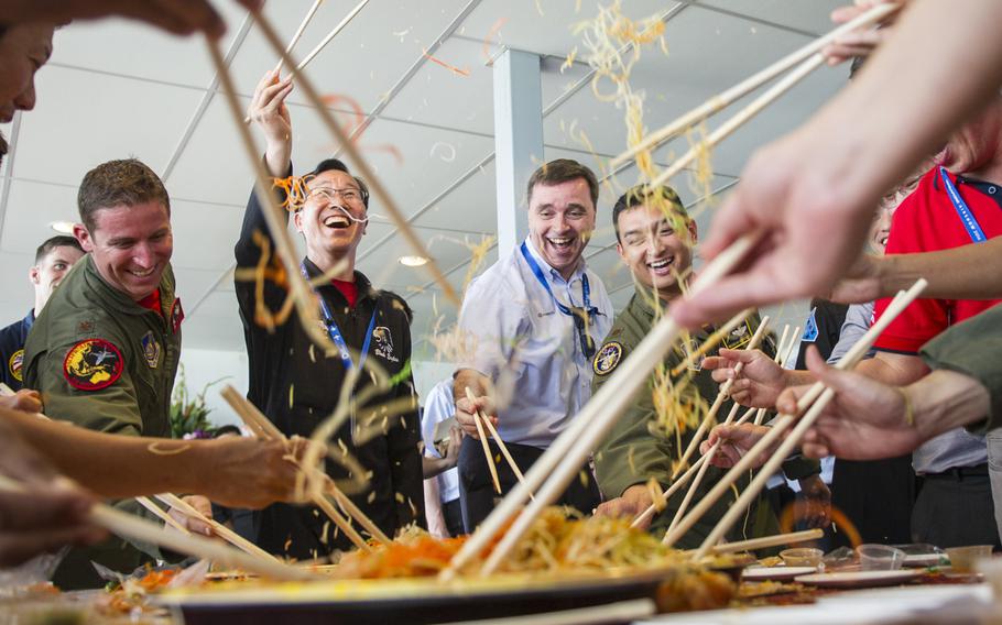 Aerial demonstration team members from the U.S., Singapore, Republic of Korea, Malaysia and France partake in the Lunar New Year tradition of a ''Lo Hei'' salad toss during a patch exchange ceremony prior to the Singapore International Airshow, at Changi Airport, Singapore, Feb. 14, 2016. The custom is meant to bring good fortune for the new year and offered airmen from several nations a fun experience to launch them into the airshow.