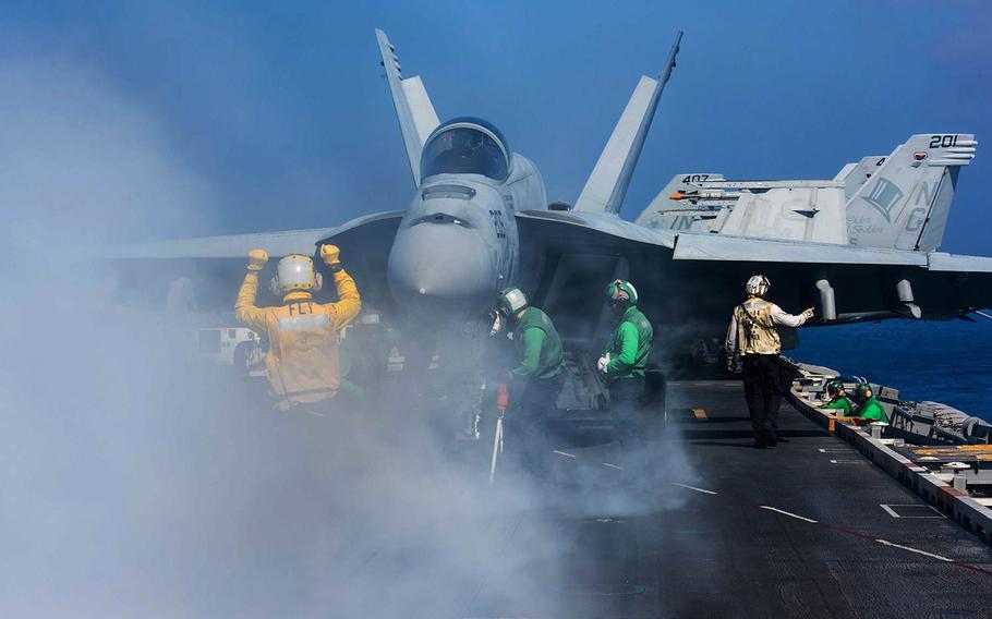 Pety Officer 2nd Class Emmanuel Bonsu, from Accra, Ghana, directs an F/A-18E Super Hornet assigned to the Tophatters of Strike Fighter Squadron 14 on the  USS John C. Stennis' flight deck on Feb. 23, 2016.