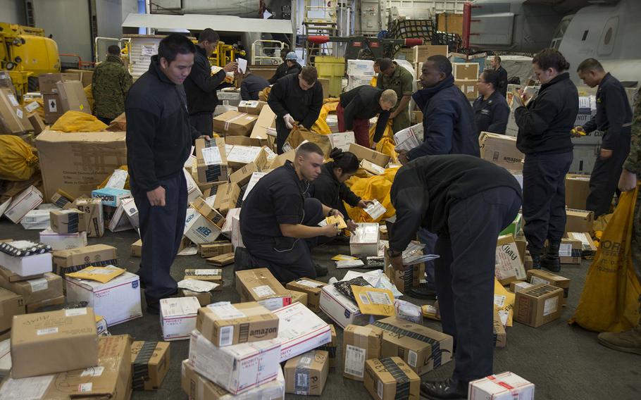Sailors sort through mail received during a replenishment at sea in the hangar bay of amphibious assault ship USS Bonhomme Richard on March 1, 2016.