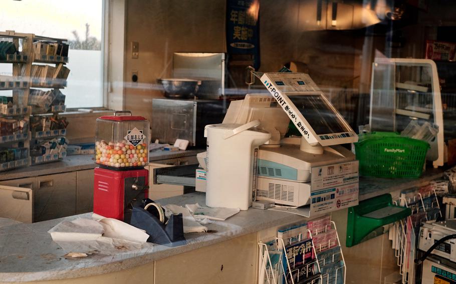 Cigarettes, gumballs and magazines are visible through the windows of an abandoned convenience store along the highway in Futaba, Japan, Feb. 10, 2016. The store has remained vacant since the city was evacuated five years ago.