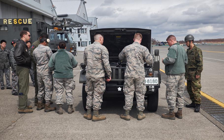 U.S. airmen and personnel from the Japan Ground Self-Defense Force inspect a Japanese military utility vehicle before loading it onto a U.S. Air Force C-130 Hercules from the 374th Airlift Wing in Chitose, Japan, Tuesday, April 19, 2016. The Yokota-based airmen arrived in Chitose, about 30 miles southeast of Sapporo, Japan, to pick up vehicles and personnel deploying to Kumamoto.