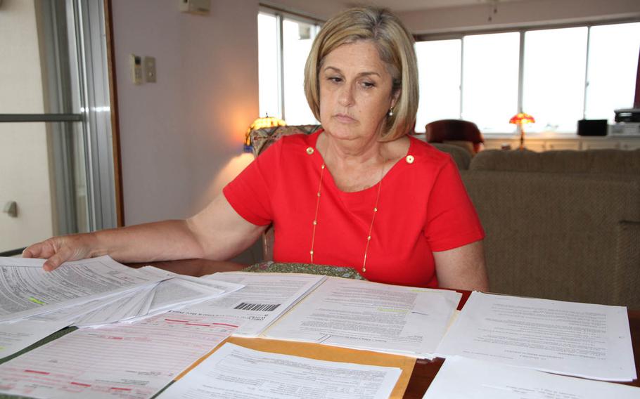 Susan Shelvock reviews paperwork from her Okinawa home related to her hospital bill payments at U.S. Naval Hospital Okinawa. Stars and Stripes spoke with a dozen families over the past seven months facing varying degrees of financial hardship in Japan and Okinawa because of recent medical billing practices.