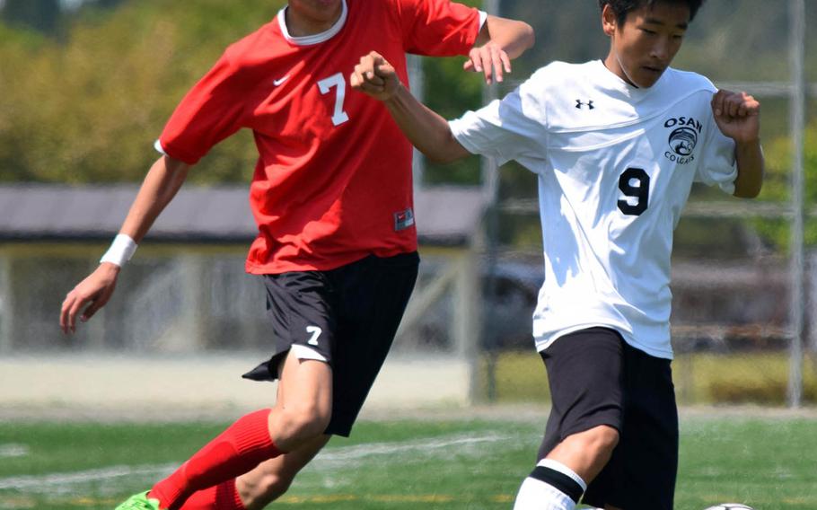 Okinawa Christian's Ryota Tsukimitsu and Osan'sMinsung Kim chase the ball during Wednesday's playoff match in the Far East Division II Boys Soccer Tournament, won by the Crusaders 4-0.