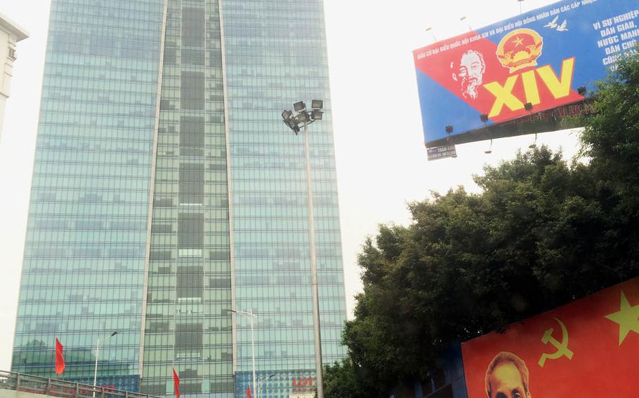 The Lotte building and its department store tower over billboard photos of Ho Chi Minh and communist symbols in Hanoi, Vietnam's capital.