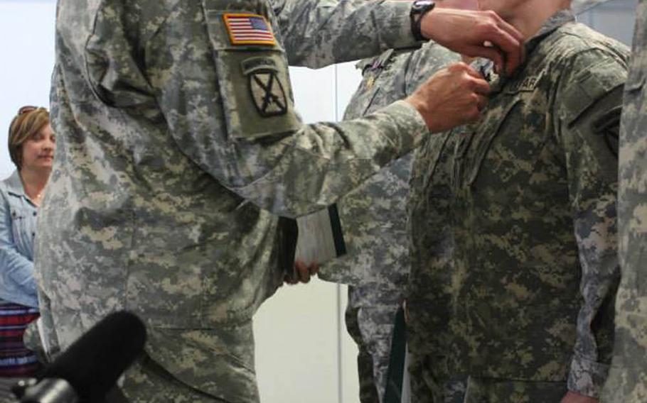 Sgt. Ryan Blomquist, an HH-60 medical evacuation helicopter crew chief, gets the Air Medal with "V" device for valor from Brigadier Gen. Michael L. Howard, 10th Mountain Division, on May 7, 2014, at Fort Drum, N.Y. 