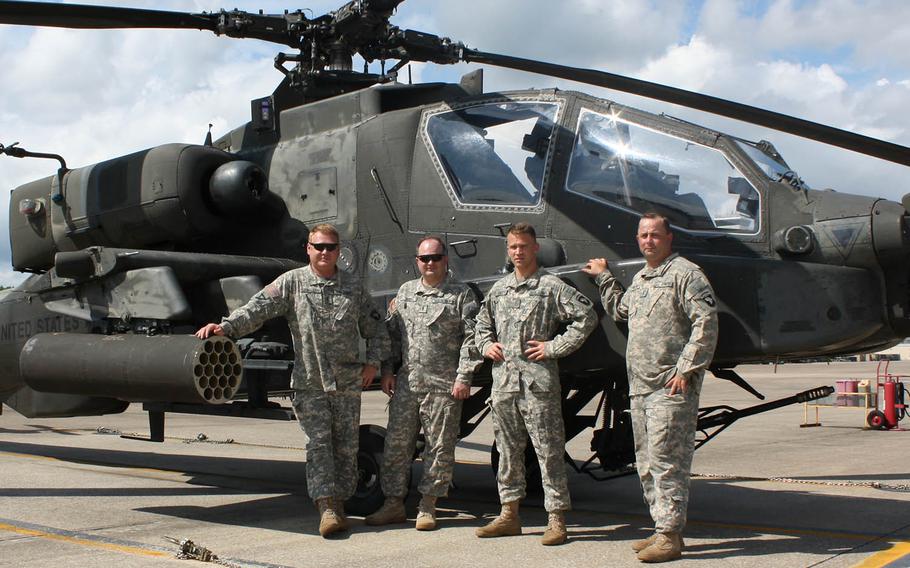 Chief Warrant Officer 3 Ross D. Lewallen, Chief Warrant Officer 3 Randy Huff, Chief Warrant Officer 2 Gary Wingert and Chief Warrant Officer 2 Christopher N. Wright pose casually in front of an AH-64 Apache, like the ones they flew over Combat Outpost Keating on Oct. 3, 2009. They received the Distinguished Flying Cross for their valor in the battle that assisted coalition forces to regain control of COP Keating. Missing are Capt. Matthew J. Kaplan and Chief Warrant Officer 2 Chad Bardwell, who also received the award.
