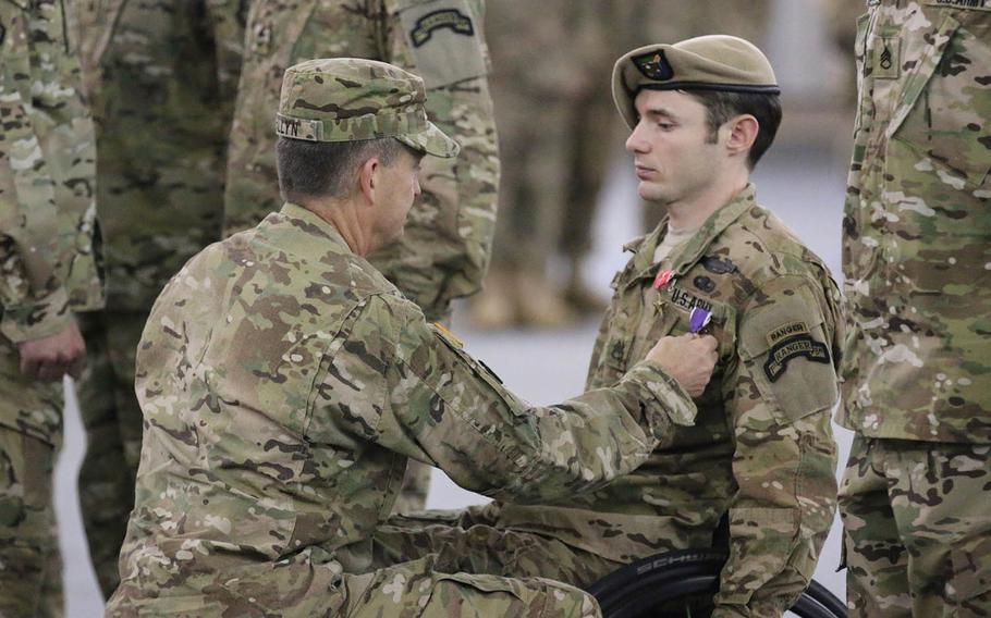 Gen. Daniel B. Allyn presents Sgt. Travis Dunn with the Bronze Star with "V" device for valor and the Purple Heart. Dunn was wounded while conducting combat operations in Nangahar province, Afghanistan, on Dec. 2, 2014.