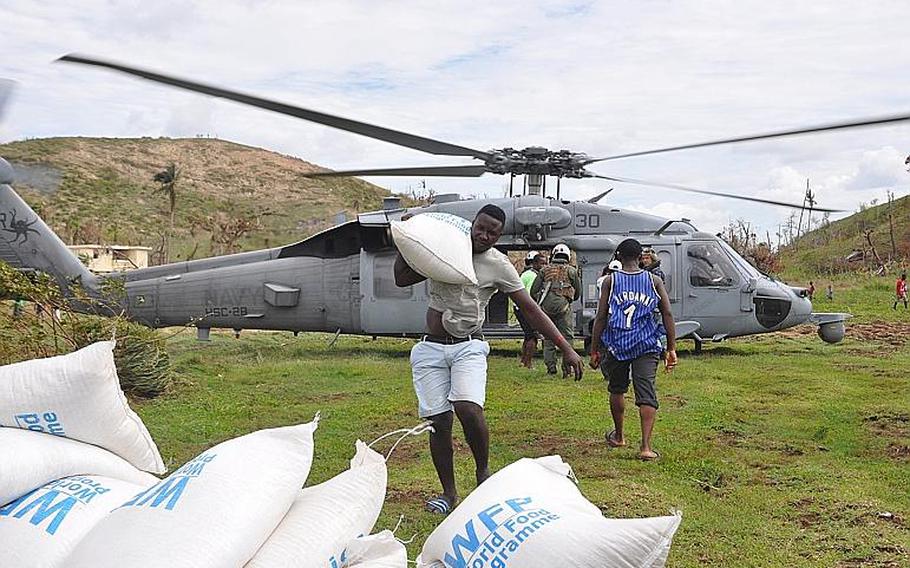 Villagers work with Navy pilots and Marines to offload relief supplies from a Navy helicopter delivered to the village of Jabouin in southwest Haiti on Oct. 18. The village was badly hit by Hurricane Matthew two weeks ago, which destroyed homes and crops, leaving many people unsheltered and without food or livelihood.