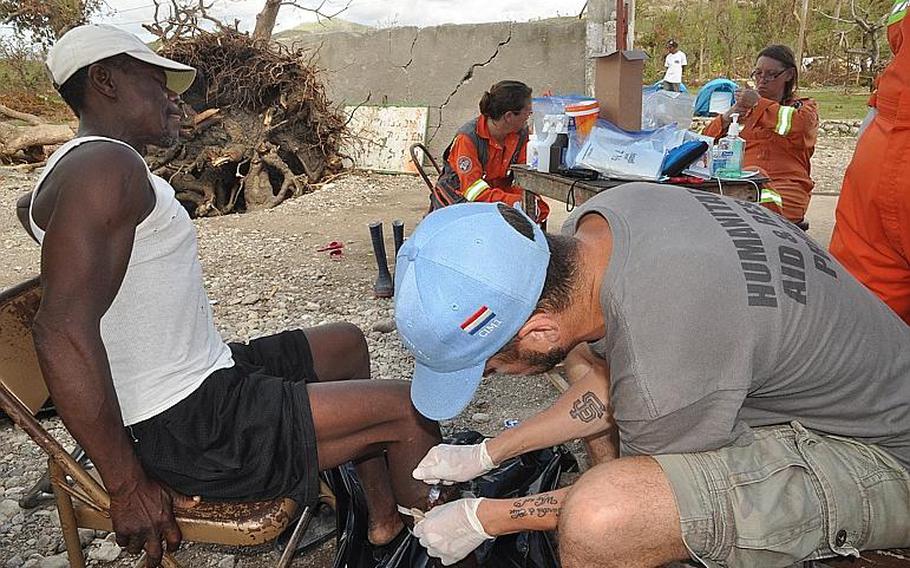 William Gagan, of the Humanitarian Aid and Rescue Project, right, tends to a deep leg wound on Jackson Bogait, a villager in the southwest Haiti village of Jabouin on Oct. 18. Bogait was wounded during Hurricane Matthew, when a piece of corrugated sheet metal off a roof flew at him during the Oct. 4 storm. 