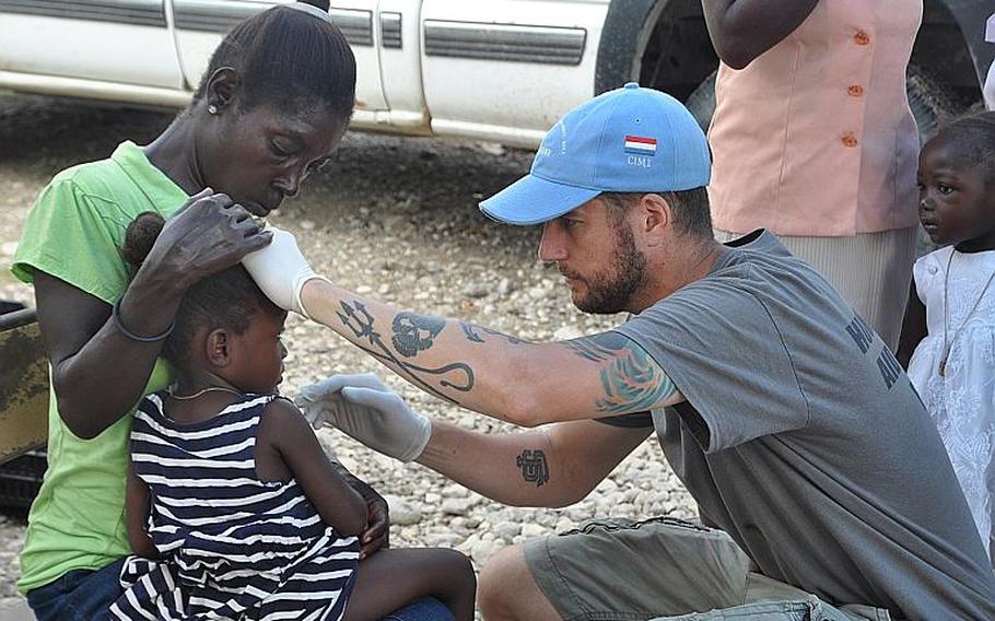 William Gagan, of the Humanitarian Aid and Rescue Project, right, tends to sick child in the southwest Haiti village of Jabouin on Oct. 18. 