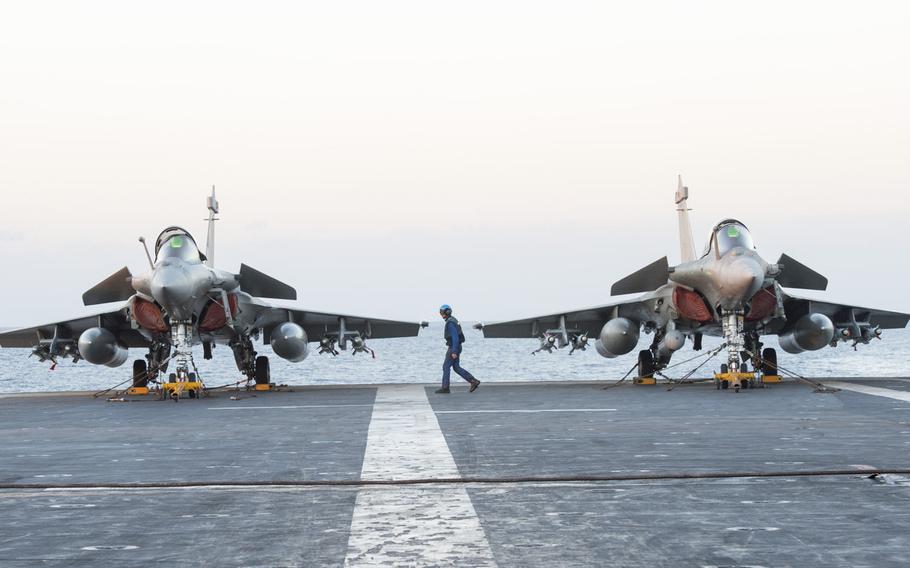 A sailor walks past two Dassault Rafale jets aboard the French navy aircraft carrier Charles de Gaulle in the eastern Mediterranean on Nov. 26, 2016.  Charles de Gaulle's air wing is bombing Islamic State targets in Iraq and Syria.
