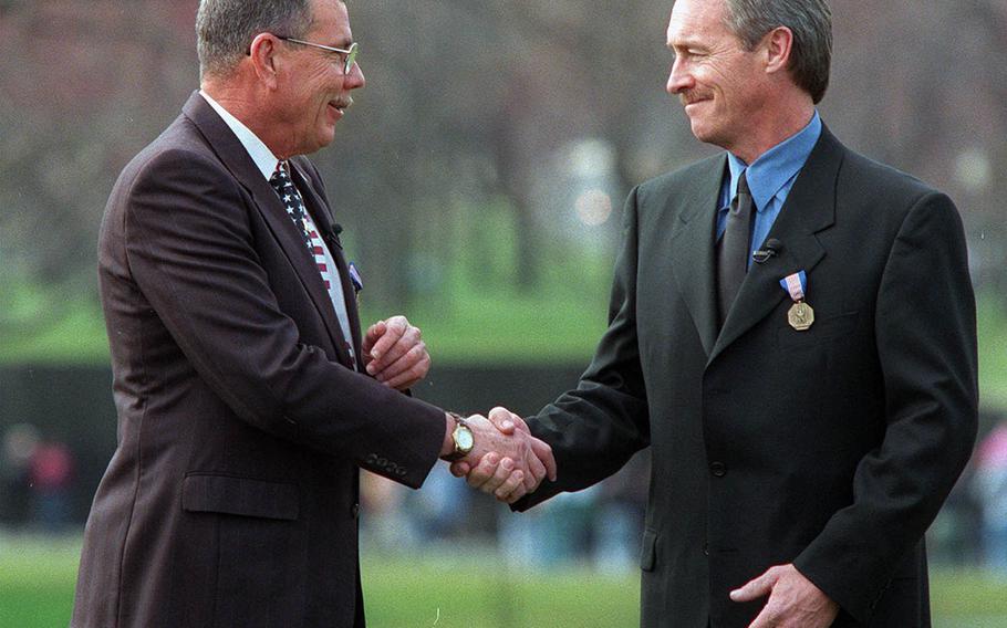 Hugh Thompson Jr., left, shakes hands with Lawrence Colburn at the Vietnam Veterans Memorial in Washington, Friday, March 6, 1998, during a ceremony where they received the Soldier's Medal. Thirty Years after aiming their weapons at fellow Americans to rescue Vietnamese civilians from the My Lai massacre, the two, along with the late Glenn Andreotta, were finally proclaimed heroes by the Army. 