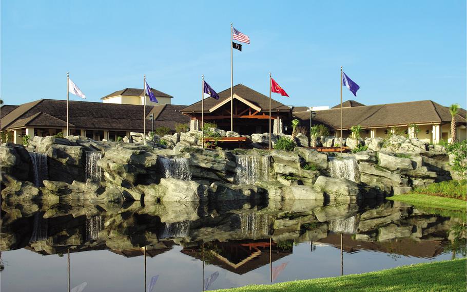 Atop an artificial rock formation, the flags of the Army, Navy, Air Force, Marines and Coast Guard flap in the breeze outside Shades of Green, a Department of Defense-owned resort for military members and their guests on the property of Walt Disney World. Inside, the clubhouse has a hunting-lodge feeling  with exposed roof beams, hewn stone and a fireplace.