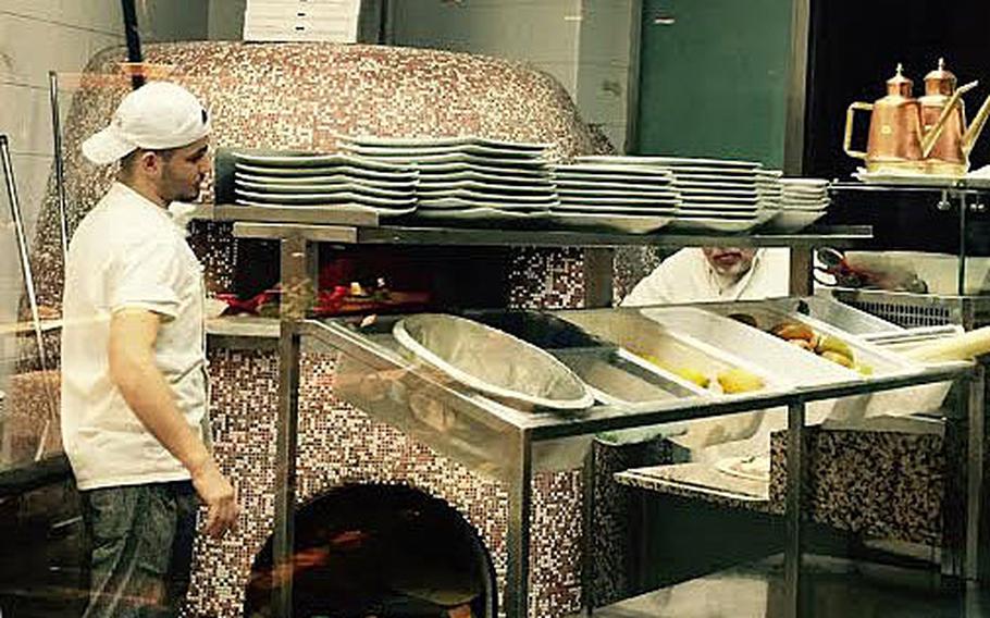 A cook prepares to remove pizza from a wood-fired oven at MMP's near the Capodichino Navy base in Naples.  The restaurant has a diverse food selection that narrows as the evening wears on.