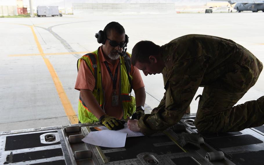 Senior Airman Ryan Berry, 26, of Bedford, Texas, right, checks a manifest at Bagram Air Field, May 4, 2017, before a C-130J flight to deliver supplies and passengers around Afghanistan.