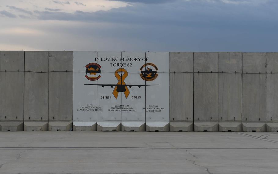 A T-Wall on the tarmac at Bagram Air Field, Afghanistan, displays a memorial to a C-130 flight and its crew.