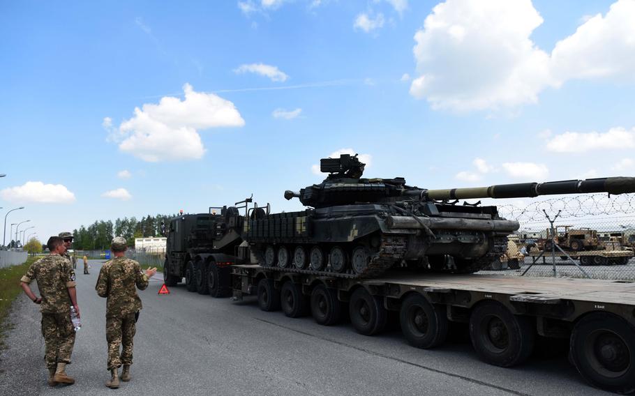 Ukrainian and American soldiers watch as a Ukrainian T-64 tank is being transported on a British Heavy Equipment Transporter, at Grafenwoehr, Germany, Tuesday, May 23.