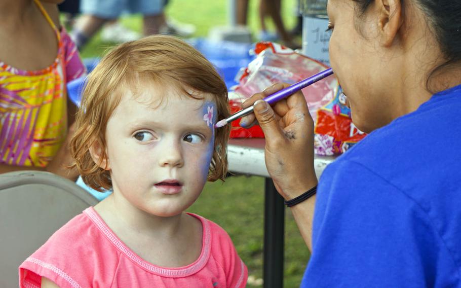 A girl tries hard to stay still as a volunteer paints her face during the Celebrate America festival at Yokota Air Base, Japan, Friday, June 30, 2017.
