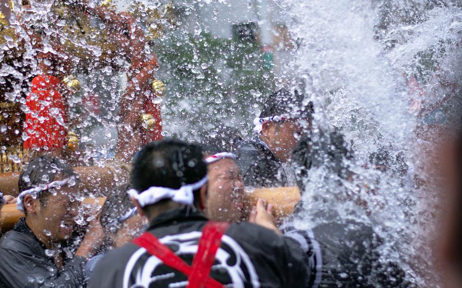Parade participants are doused with water as they carry a portable Shinto shrine, called a mikoshi, through the streets of central Tokyo, Sunday, Aug. 13, 2017.