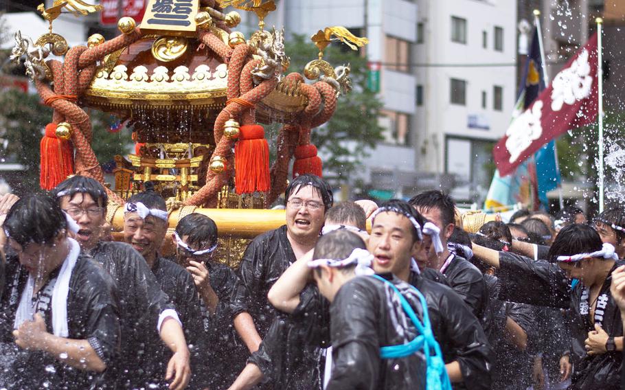 People carrying a miniature Shinto shrine called a mikoshi are drenched with water during the Fukagawa Hachiman Matsuri in Tokyo, Sunday, Aug. 13, 2017.