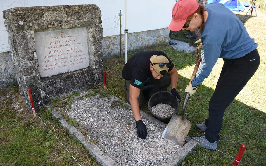 Joan Baker, an anthropologist, and Marine Corp. Julian Temblador remove small stones from the top of a grave next to a church in Pokojisce, Slovenia, on July 17, 2017. A team representing the Defense POW/MIA Accounting Agency conducted a mission in Slovenia in July to search for the remains of Sgt. Alfonso Duran, an airman missing since World War II.