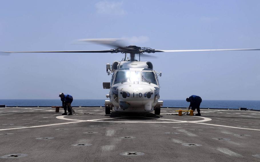 Sailors aboard the USS Carter Hall remove chocks and chains from a Japan Maritime Self-Defense Force SH-60J Seahawk helicopter during a counter-piracy exercise on April 20, 2017.