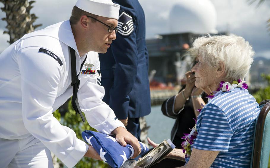 A member of Joint Base Pearl Harbor-Hickam's honors and ceremonial guard unit presents the national ensign to Emily Stone, wife of Pearl Harbor survivor Melvin Stone, at the USS Utah Memorial, Tuesday, Sept. 19, 2017.