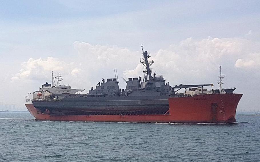 The guided missile destroyer USS John S. McCain departs Singapore on the heavy-lift transport MV Treasure, Oct. 11, 2017.