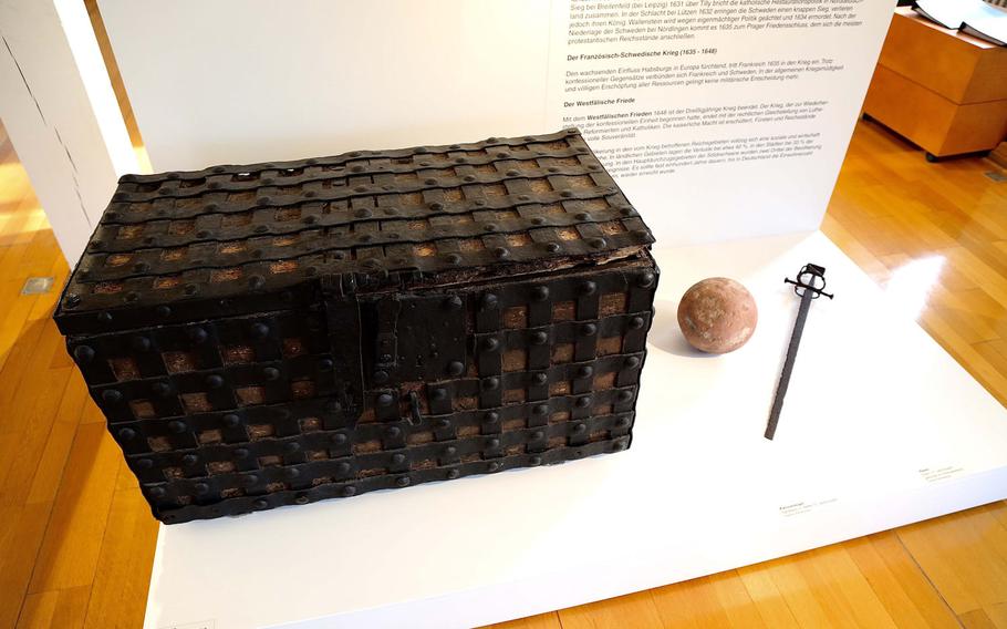 A chest, stone canon ball and sword on display in at the Theodor-Zink-Museum in Kaiserslautern, Germany. The chests were used to safeguard valuables and important deeds during fires and in times of war. The city has been destroyed and rebuilt no fewer than three times since the Middle Ages.