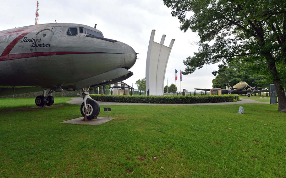A C-54 Skymaster stands in the foreground at the Berlin Airlift Memorial on the edge of Frankfurt, Germany's largest international airport. At center is the monument; in the background is a C-47.