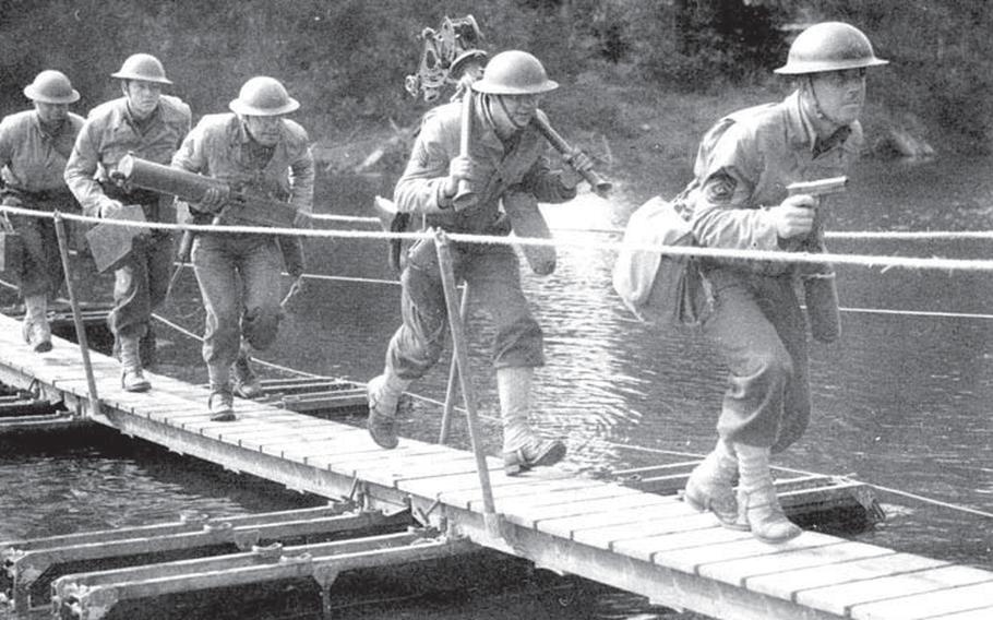Led by their sergeant with his M1911 in hand, a .30-caliber machine gun team crosses a bridge during maneuvers in August 1941.