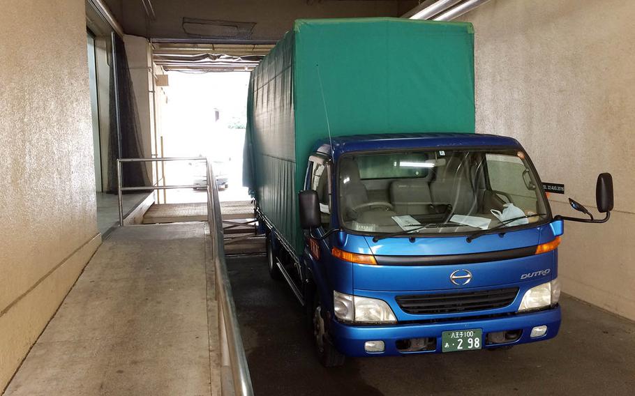 A moving truck parks underneath a housing tower at Yokota Air Base, Japan, Tuesday, June 12, 2018.
