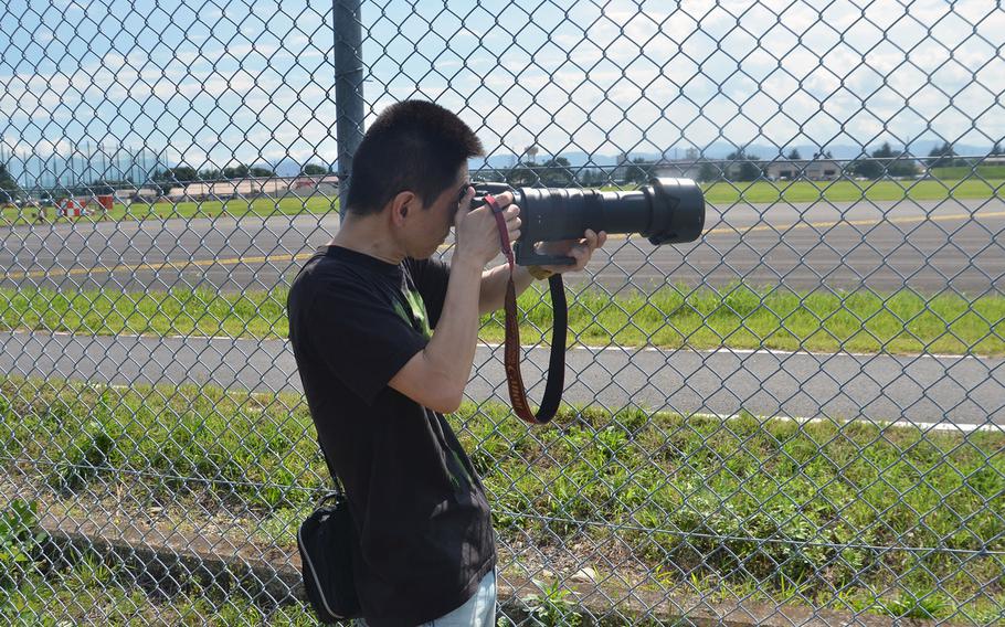 Military aircraft enthusiast Terutsugu Yamaguchi, 46, from Tokyo, photographs F-22 Raptor stealth fighters through the fence at Yokota Air Base, Japan, on July 9, 2018.