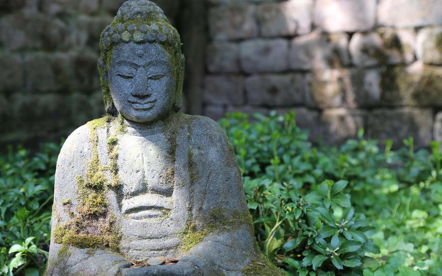 A statue of Buddha sits in a secluded corner of the Japanese Garden at Kaiserslautern, Germany.
