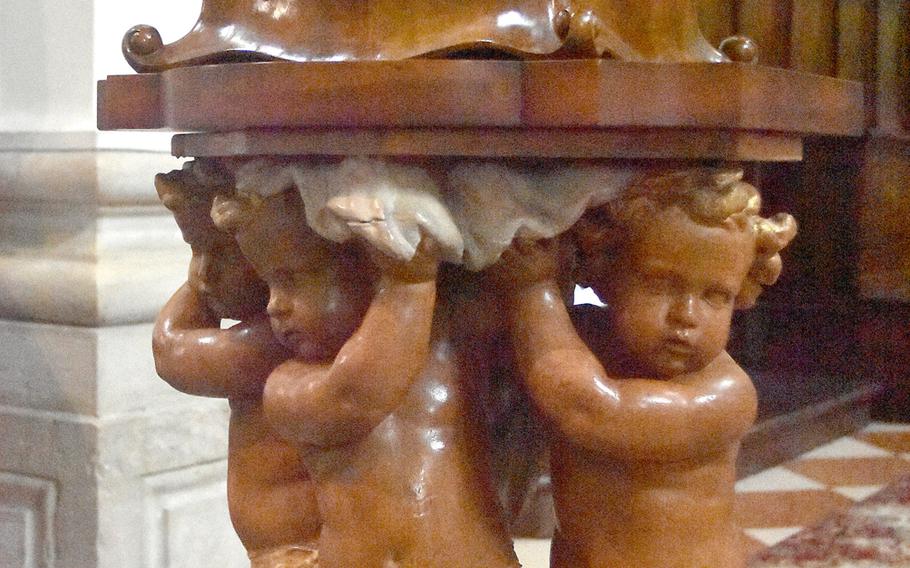 Three cherubs carved from wood hold up the pulpit in the Duomo di San Andrea in Portogruaro, Italy.