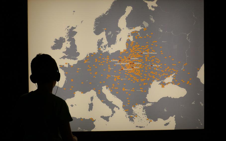 A boy listens to the description of the ''Room of Sites,'' while looking at a map that marks sites around Europe where Jews were persecuted and murdered.