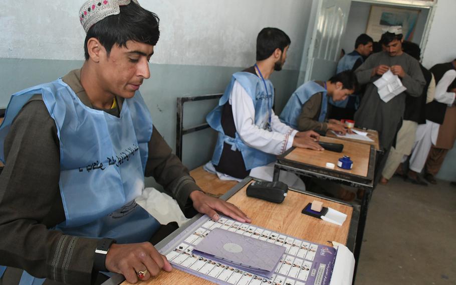 Election officials wait to assist voters who are casting their ballots in Kandahar's delayed parliamentary elections on Saturday, Oct. 27, 2018. 