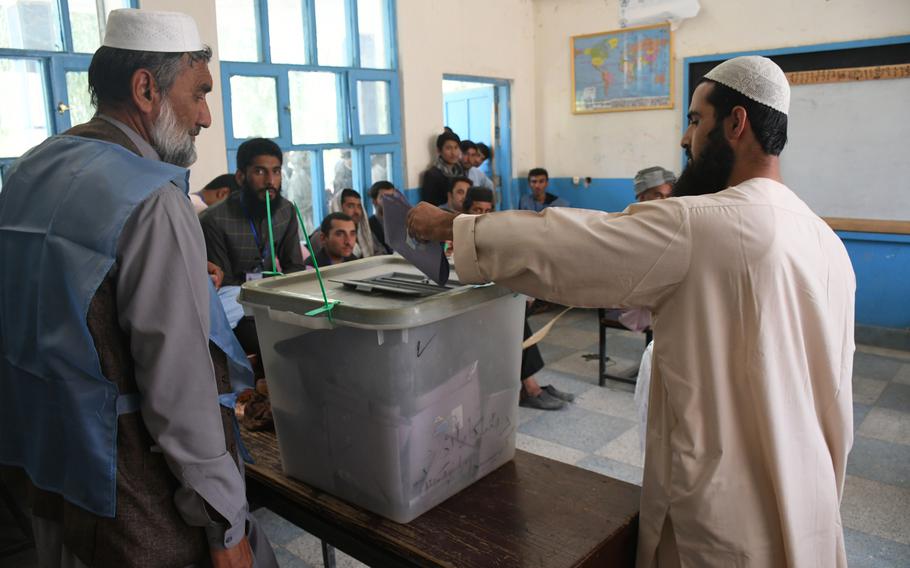 A voter in Kandahar, Afghanistan, casts his ballot in delayed parliamentary elections as election observers watch on Saturday, Oct. 27, 2018. 

