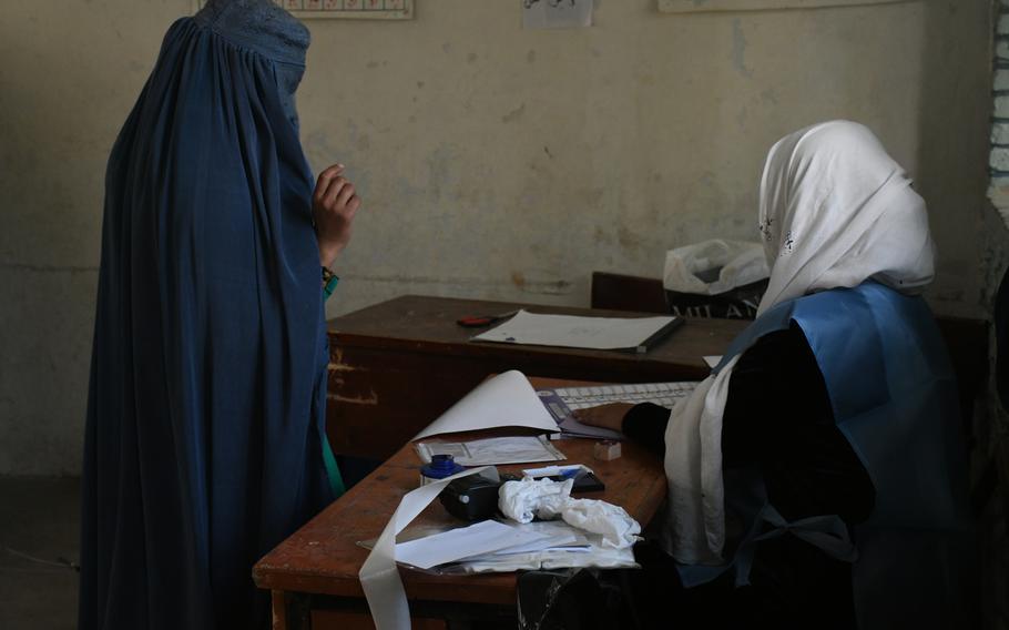 A woman in Kandahar, Afghanistan, receives her ballot to vote in parliamentary elections on Saturday, Oct. 27, 2018. 

