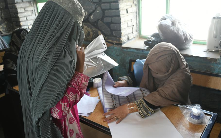 A woman in Kandahar, Afghanistan, receives her ballot to vote in parliamentary elections on Saturday, Oct. 27, 2018.