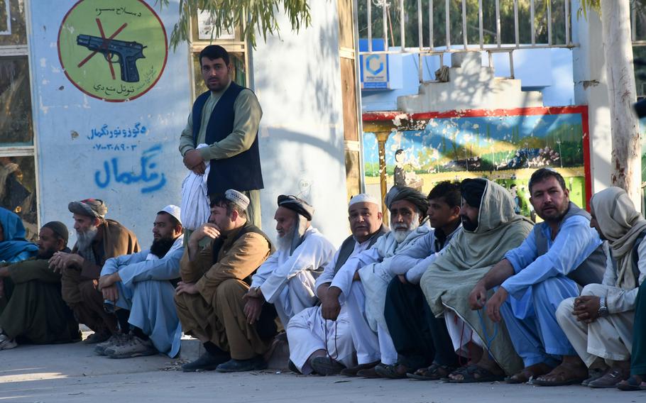 Men wait to vote at a polling center in Kandahar's Aino Maina neighborhood. The center opened late on Saturday, Oct. 27, 2018, because staff had difficulties using the biometric identification machines.